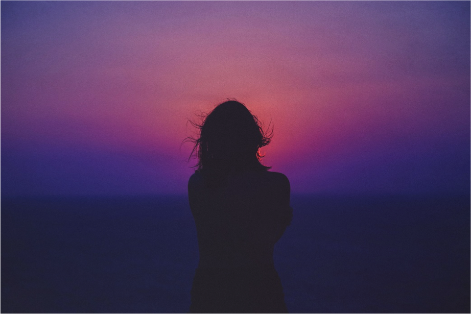 Mujer de espaldas viendo una puesta de sol